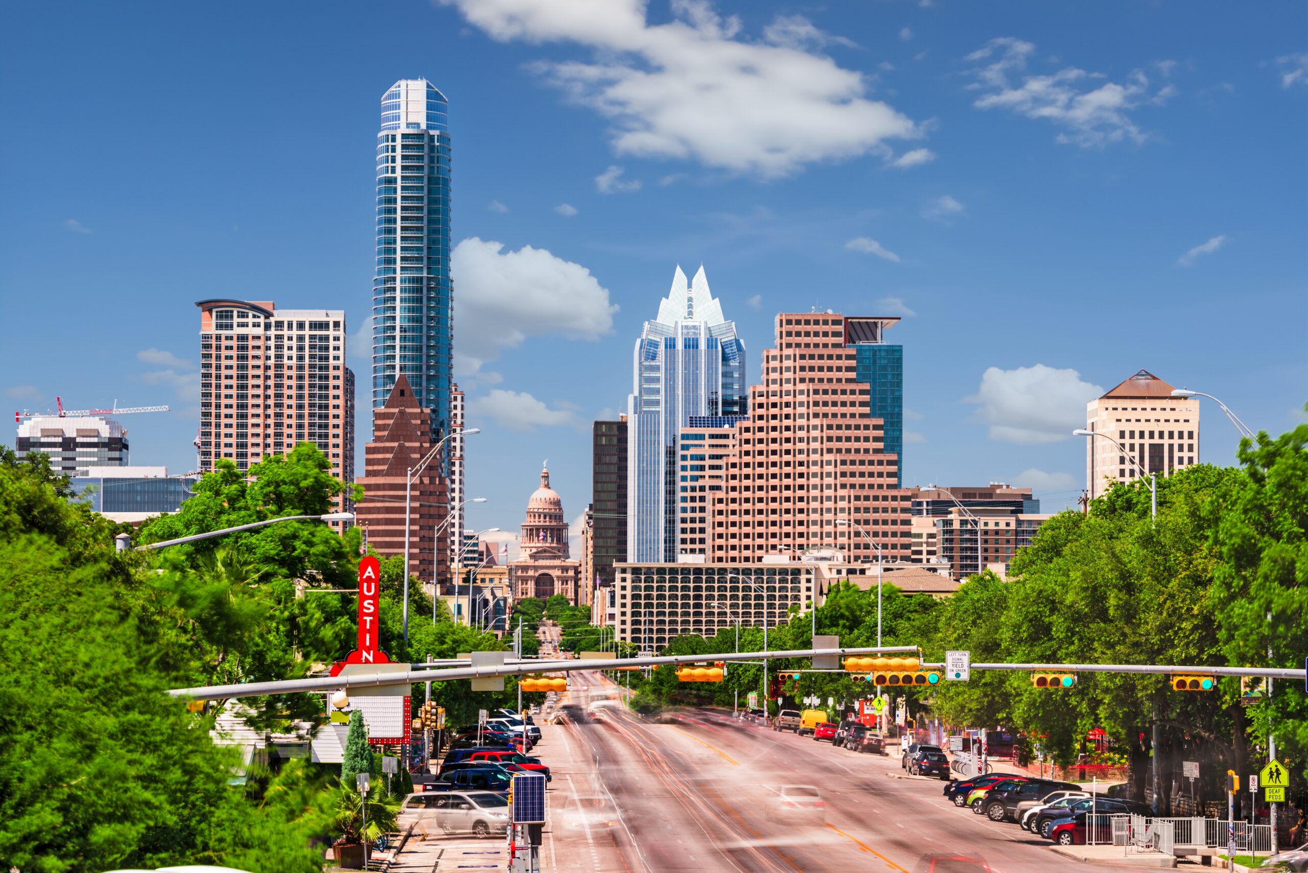 Austin,,Texas,,Usa,Downtown,Cityscape,On,Congress,Avenue. Austin, Texas skyline featuring the Texas State Capitol surrounded by modern skyscrapers, with a clear blue sky and light traffic on the main road.